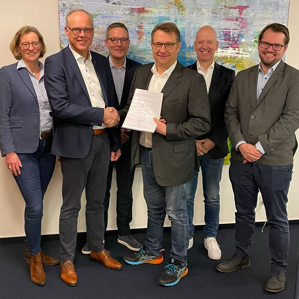 Nach der Vertragsunterzeichnung: Händedruck mit Gesellschaftervertrag und allen sechs Gesellschaftern. Vorne: Andreas Boenke (links) mit Hans-Joachim Meinert